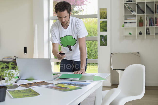 Man holding mobile phone and working on laptop — Stock Photo