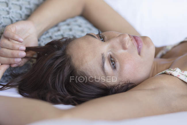 Nahaufnahme einer nachdenklichen Frau, die auf dem Bett liegt und denkt — Stockfoto