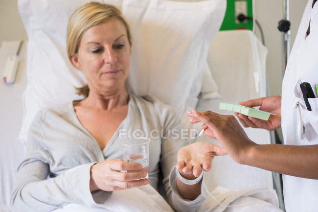 Krankenschwester gibt Patientin Pille auf Krankenhausbett — Stockfoto