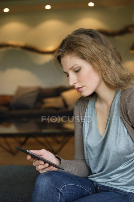 Серьёзная женщина с цифровым планшетом на диване в номере — стоковое фото
