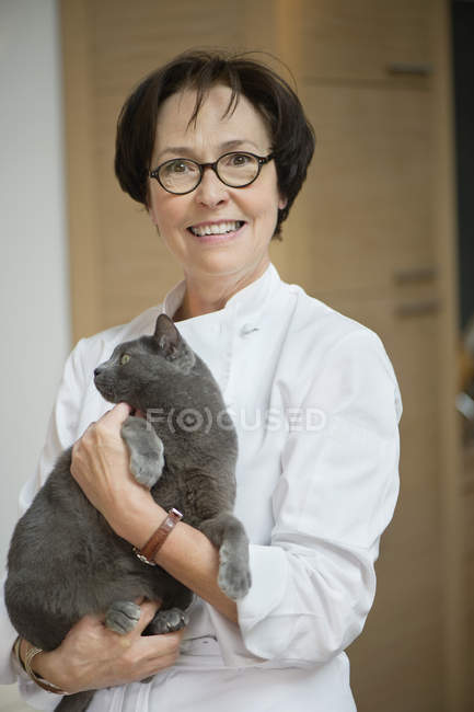 Портрет зрелой женщины, держащей кота и улыбающейся — стоковое фото