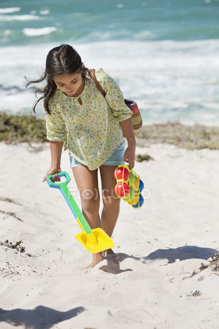 Menina carregando pá e brinquedo na praia de verão — Fotografia de Stock