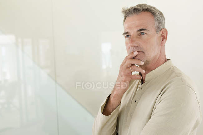 Вдумчивый взрослый мужчина, стоящий перед стеной — стоковое фото