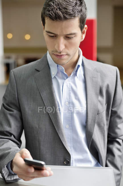Primo piano di fiducioso giovane uomo d'affari messaggistica con il telefono cellulare — Foto stock