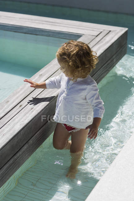 Bonito bebê menina jogar na água no infinito piscina — Fotografia de Stock