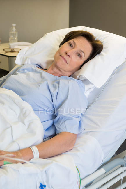 Smiling mature woman lying in hospital bed and looking at camera — Stock Photo