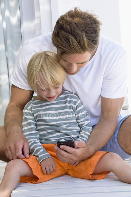 Feliz padre e hijo usando el teléfono - foto de stock