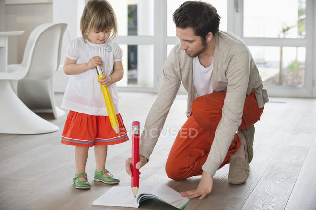 Man and daughter writing with big pencils — Stock Photo