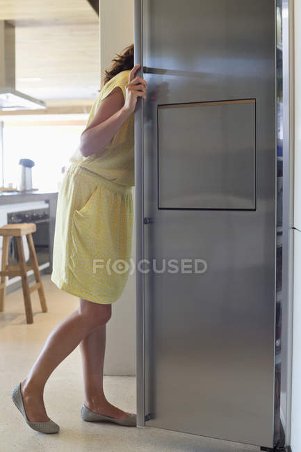 Mulher olhando para a geladeira na cozinha moderna — Fotografia de Stock