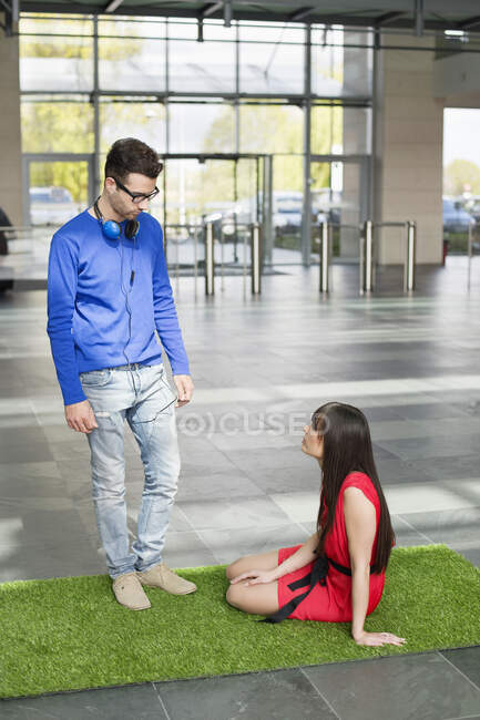 Business executives relaxing on grass mat in an office lobby — Stock Photo