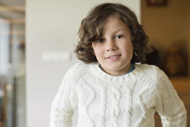Retrato de lindo niño sonriente en jersey blanco en casa - foto de stock