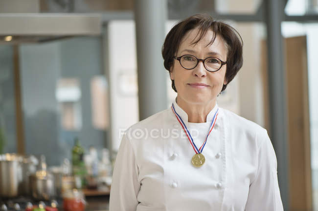 Портрет пожилой женщины улыбающейся в костюме шеф-повара с медалью — стоковое фото