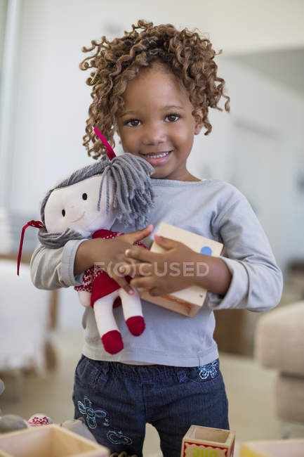 Retrato de niña sosteniendo muñeca de trapo y cubo - foto de stock