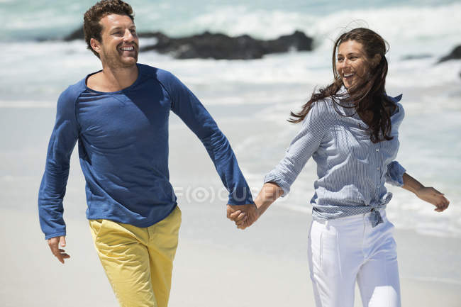 Coppia che cammina sulla spiaggia sabbiosa tenendosi per mano — Foto stock