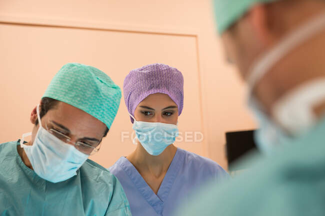 Equipo médico realizando una operación en un quirófano - foto de stock
