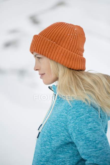 Крупный план женщины в вязаной шляпе, смотрящей на улицу зимой — стоковое фото