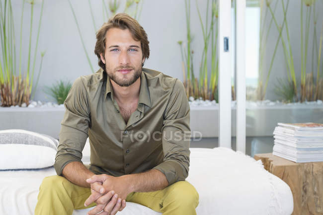 Young bearded Man sitting at home and looking at camera — Stock Photo