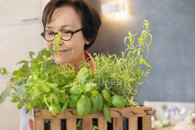Улыбающаяся женщина нюхает травы в горшке — стоковое фото