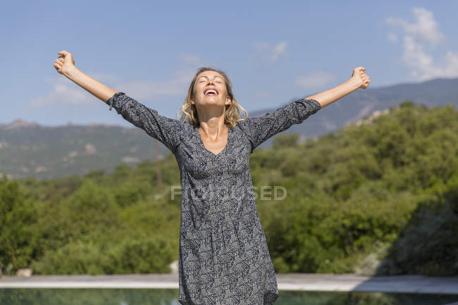 Щаслива жінка з простягнутими руками стоячи в горах — стокове фото