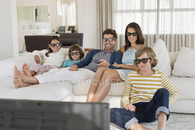 Сім'я дивиться телевізор вдома під час носіння 3D окулярів — стокове фото