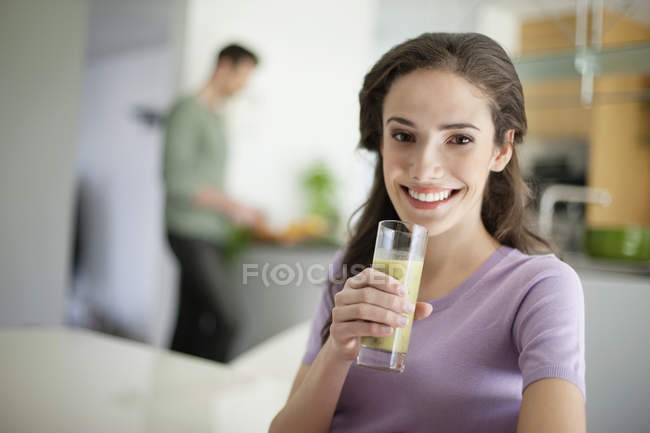 Donna che tiene un bicchiere di frullato vegetale e sorride — Foto stock