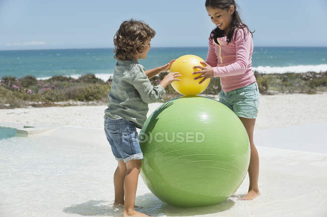 Crianças brincando na praia de areia com bolas — Fotografia de Stock
