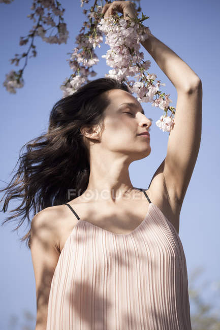 Портрет розслабленої жінки з закритими очима позує з квітами на відкритому повітрі — стокове фото