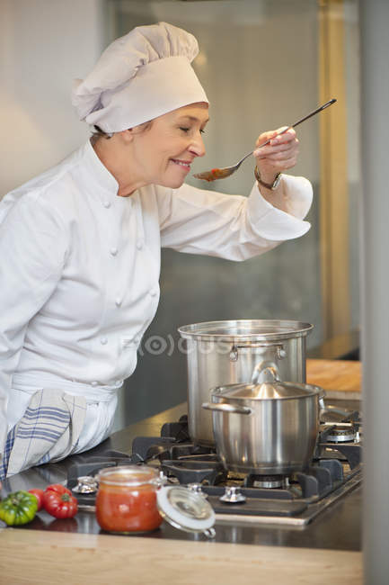 Frau im Kochkostüm kocht Essen in der Küche — Stockfoto