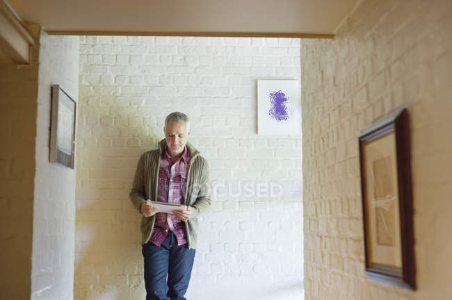 Uomo che utilizza tablet digitale in un corridoio a casa — Foto stock