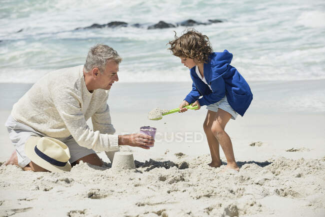 Мальчик играет со своим дедушкой на пляже — стоковое фото