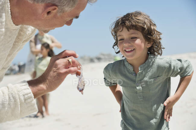 Чоловік показує медузу своєму онуку на пляжі — стокове фото