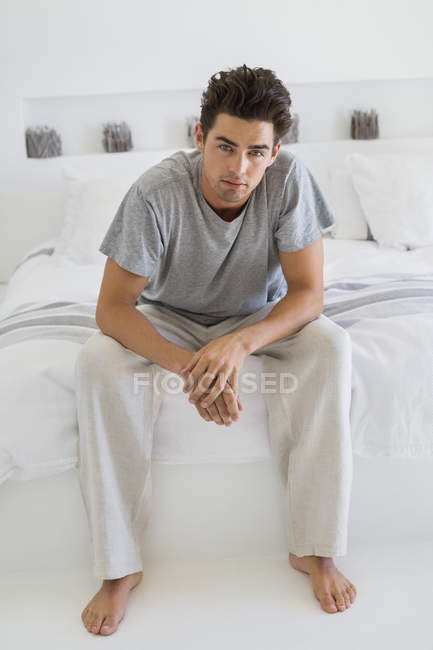 Portrait of barefoot man sitting on bed — Stock Photo