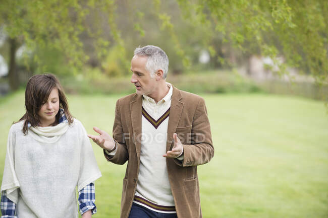Мужчина, обсуждающий со своей дочерью во время прогулки в парке — стоковое фото