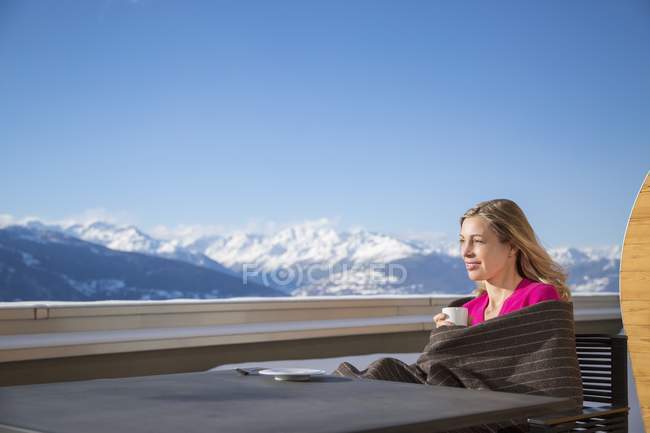 Mujer tomando café en la terraza con vistas a las montañas, Crans-Montana, Alpes suizos, Suiza - foto de stock