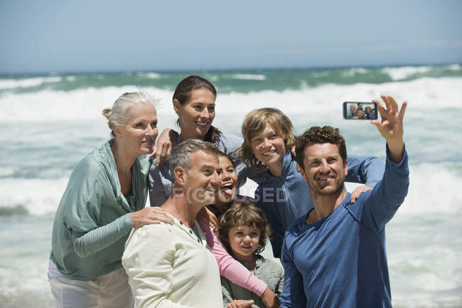 Портрет счастливой многодетной семьи, делающей селфи с мобильным телефоном на пляже — стоковое фото