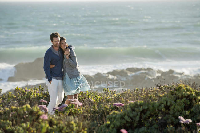 Couple souriant embrassant debout sur la côte de la mer — Photo de stock