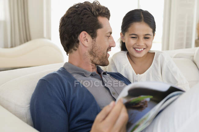 Чоловік і його дочка читають журнал. — стокове фото