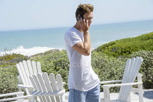 Jovem falando no celular no terraço costeiro — Fotografia de Stock