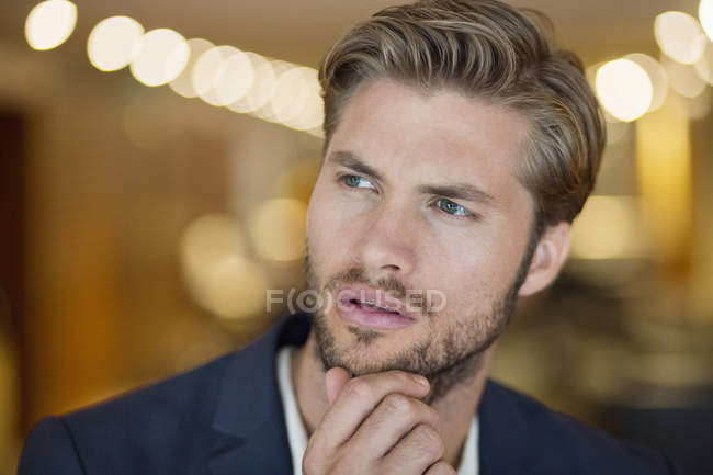 Primer plano del joven guapo mirando hacia otro lado mientras pensaba - foto de stock