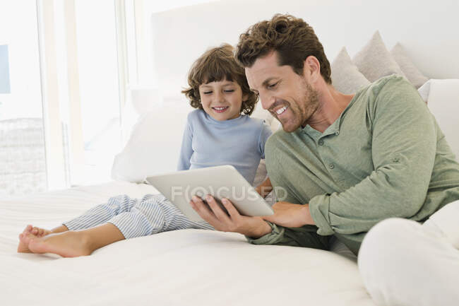 Человек показывает цифровой планшет своему сыну — стоковое фото