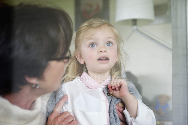 Woman with her granddaughter near a window — Stock Photo