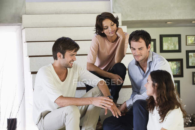 Smiling friends sitting on steps talking to each other — Stock Photo