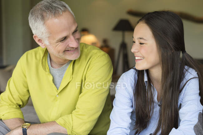 Hombre y su hija sonriendo en casa - foto de stock