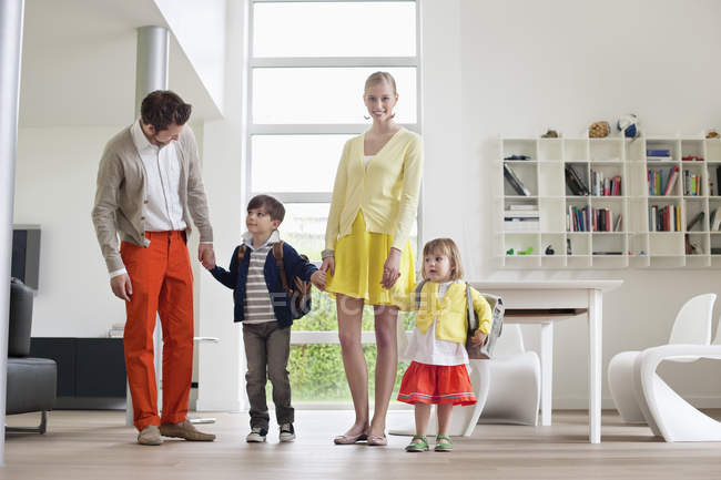 Casal feliz com crianças pequenas em pé no apartamento moderno — Fotografia de Stock