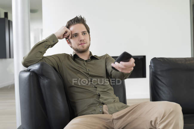 Giovane uomo positivo che guarda la televisione sul divano a casa — Foto stock