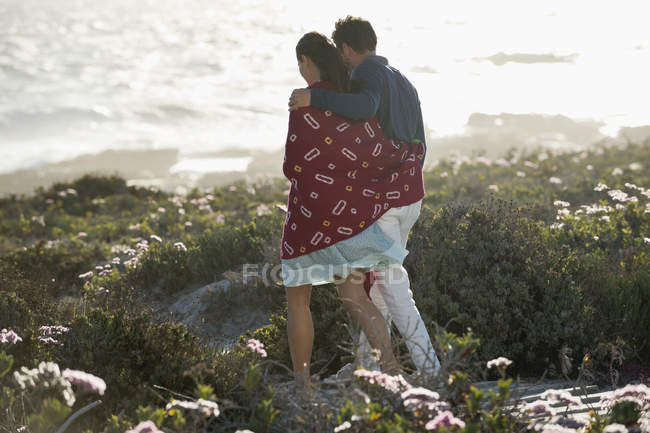 Abraçando casal andando na costa ensolarada — Fotografia de Stock