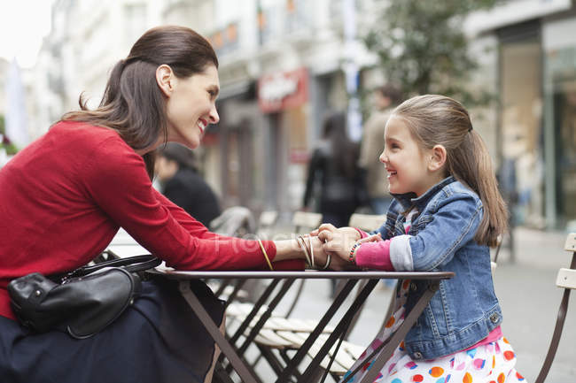 Happy woman and little daughter sitting at sidewalk cafe — Stock Photo