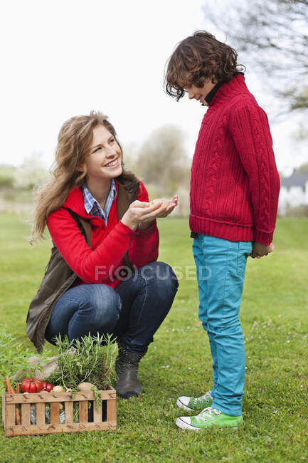 Femme montrant des légumes à son fils — Photo de stock
