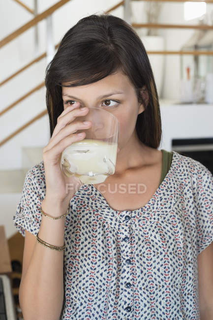Портрет молодой женщины, пьющей стакан сока дома — стоковое фото