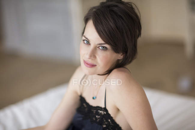 Retrato de mulher elegante em roupa de noite sentado na cama — Fotografia de Stock
